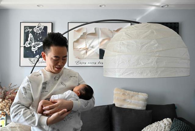 Zhu Yunfei holds his newborn baby Zhu Wanning in Langfang, northern China's Hebei province on March 6, 2026. The world's second-most populous country is threatened with a demographic crisis after its birth rate halved over the past decade -- all while people rapidly age out of the workforce. (Photo by Adek BERRY / AFP) / TO GO WITH AFP STORY: China-economy-demographics-infants, by Mary YANG