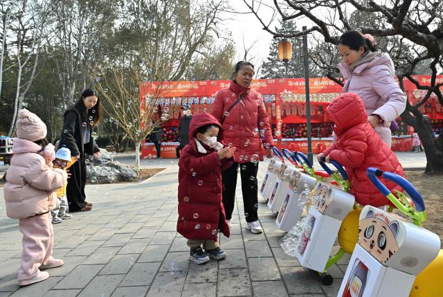 Families visit a park in Beijing on March 7, 2026. The world's second-most populous country is threatened with a demographic crisis after its birth rate halved over the past decade -- all while people rapidly age out of the workforce. (Photo by Adek BERRY / AFP) / TO GO WITH AFP STORY: China-economy-demographics-infants, by Mary YANG