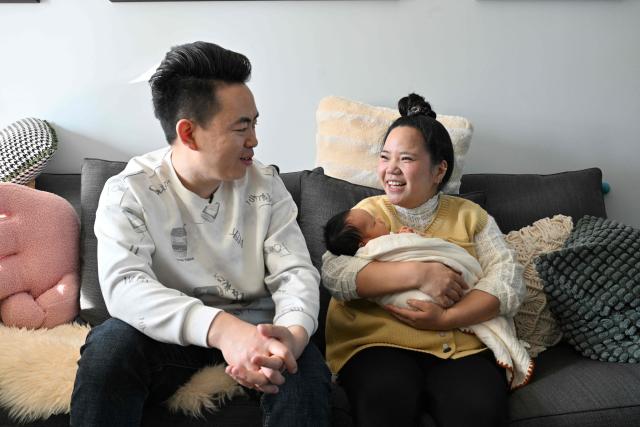 Zhang Xiaofei (R) holds her baby Zhu Wanning next to her husband Zhu Yunfei (L) in Langfang, northern China's Hebei province on March 6, 2026. The world's second-most populous country is threatened with a demographic crisis after its birth rate halved over the past decade -- all while people rapidly age out of the workforce. (Photo by Adek BERRY / AFP) / TO GO WITH AFP STORY: China-economy-demographics-infants, by Mary YANG