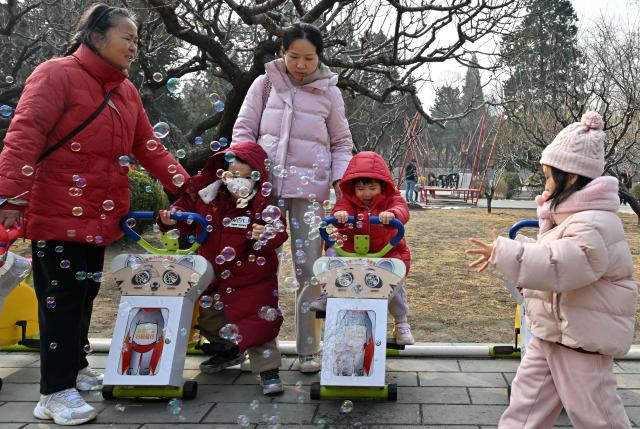 Families visit a park in Beijing on March 7, 2026. The world's second-most populous country is threatened with a demographic crisis after its birth rate halved over the past decade -- all while people rapidly age out of the workforce. (Photo by Adek BERRY / AFP) / TO GO WITH AFP STORY: China-economy-demographics-infants, by Mary YANG