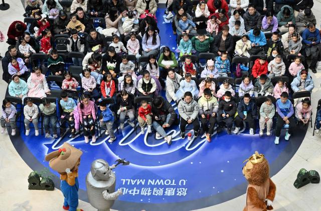 Parents and children watch a children's drama in Beijing on March 7, 2026. The world's second-most populous country is threatened with a demographic crisis after its birth rate halved over the past decade -- all while people rapidly age out of the workforce. (Photo by Adek BERRY / AFP) / TO GO WITH AFP STORY: China-economy-demographics-infants, by Mary YANG
