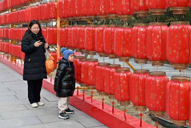A woman and a child visit a park in Beijing on March 7, 2026. The world's second-most populous country is threatened with a demographic crisis after its birth rate halved over the past decade -- all while people rapidly age out of the workforce. (Photo by Adek BERRY / AFP) / TO GO WITH AFP STORY: China-economy-demographics-infants, by Mary YANG