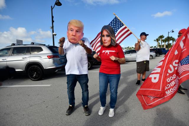 Supporters of Donald Trump wear masks depicting Trump and Melania Trump near Mar-a-Lago in Palm Beach, Florida, on March 7, 2026. (Photo by Octavio JONES / AFP)