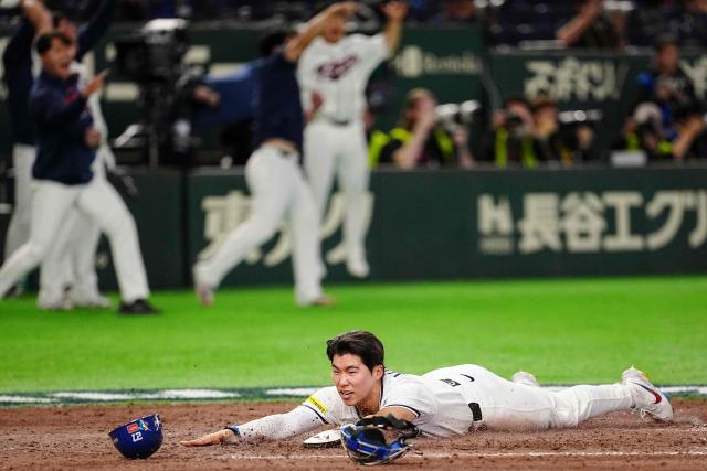 South Korea's Kim Hye-seong (bottom) scores as Kim Do-yeong (not pictured) hits a double during the World Baseball Classic (WBC) Pool C game between Taiwan and South Korea at the Tokyo Dome in Tokyo on March 8, 2026. (Photo by Yuichi YAMAZAKI / AFP)