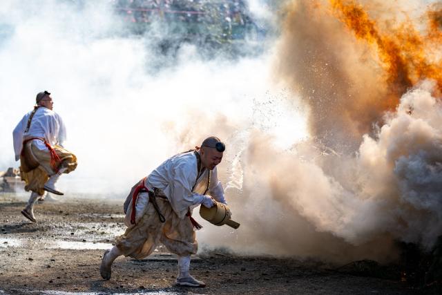 Buddhist monk throws water over a burning sacred fire during the annual "Hiwatari Matsuri", known as fire walking festival, at the Takaosan Yakuoin Temple in Hachioji area, the western portion of the Tokyo Metropolis on March 8, 2026. (Photo by Philip FONG / AFP)