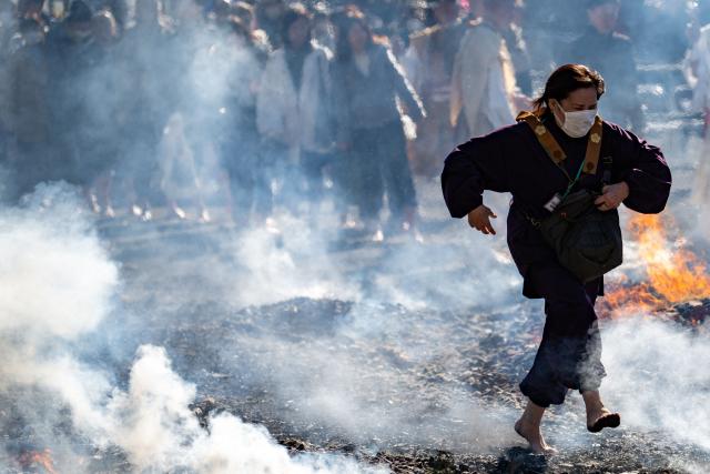 A woman walks barefoot over coal during the annual "Hiwatari Matsuri", known as fire walking festival, at the Takaosan Yakuoin Temple in Hachioji area, the western portion of the Tokyo Metropolis on March 8, 2026. (Photo by Philip FONG / AFP)