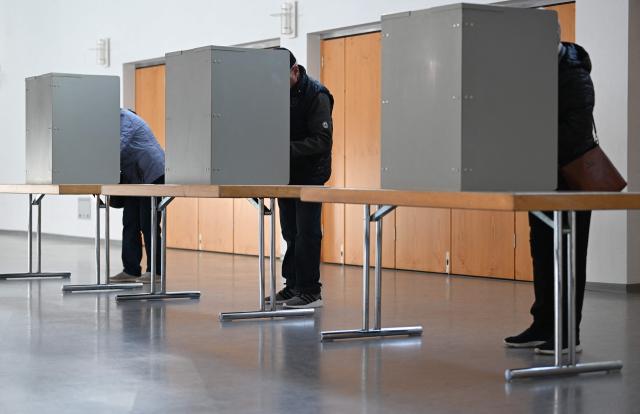Voters stand behind voting booths to fill out their ballot papers at a polling station in Gutach, southwestern Germany, on March 8, 2026, during the state election in the German federal state of Baden-Wuerttemberg. Voters head to the polls on March 8 in the southwestern state of Baden-Wuerttemberg, a prosperous hub of Germany's flagship auto sector with a population of 11.2 million. (Photo by THOMAS KIENZLE / AFP)