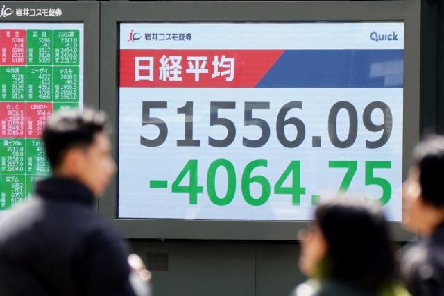 Pedestrians walk past an electronic quotation board displaying the Nikkei Stock Average on the Tokyo Stock Exchange in Tokyo on March 9, 2026. Asian stock markets plunged March 9 as oil prices soared 30 percent on fears about supplies from the Middle East as the US-Israeli war against Iran continued into a second week with no sign of letting up. (Photo by Kazuhiro NOGI / AFP)
