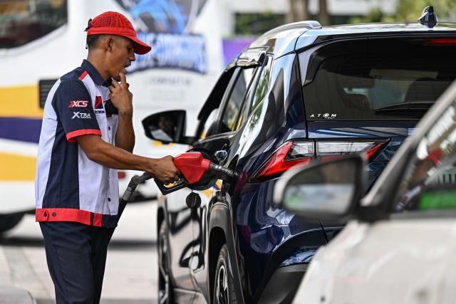 An employee fills up a car at at a gas station amid rising petrol prices in Quezon City, Metro Manila on March 9, 2026. The price of the main US benchmark for oil surged more than 30 percent on March 9, 2026 over concerns that the Middle East war could create prolonged supply disruptions. (Photo by Jam STA ROSA / AFP)