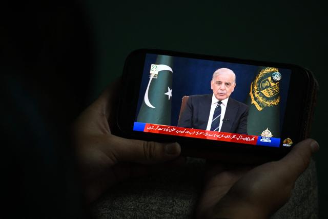 A resident listens on his mobile phone to an address to the nation by Pakistan’s Prime Minister Shehbaz Sharif about the ongoing US-Israel conflict with Iran, in Islamabad on March 9, 2026. The Iran war sent oil prices spiralling above $100 a barrel on March 9 after Tehran under new leader Mojtaba Khamanei fired a new barrage of missiles at Israel and its crude-exporting Gulf neighbours. (Photo by Aamir QURESHI / AFP)