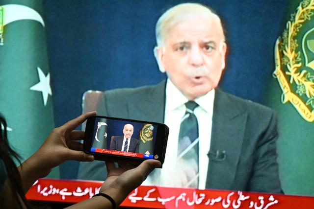 A resident listens on a mobile phone to an address to the nation by Pakistan’s Prime Minister Shehbaz Sharif about the ongoing US-Israel conflict with Iran, in Islamabad on March 9, 2026. The Iran war sent oil prices spiralling above $100 a barrel on March 9 after Tehran under new leader Mojtaba Khamanei fired a new barrage of missiles at Israel and its crude-exporting Gulf neighbours. (Photo by Aamir QURESHI / AFP)