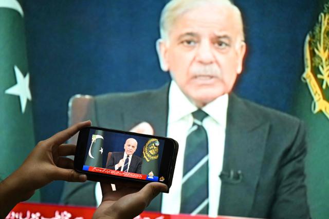 A resident listens on a mobile phone to an address to the nation by Pakistan’s Prime Minister Shehbaz Sharif about the ongoing US-Israel conflict with Iran, in Islamabad on March 9, 2026. The Iran war sent oil prices spiralling above $100 a barrel on March 9 after Tehran under new leader Mojtaba Khamanei fired a new barrage of missiles at Israel and its crude-exporting Gulf neighbours. (Photo by Aamir QURESHI / AFP)