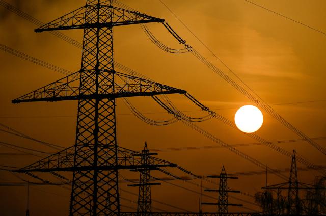 A photo shows electricity pylons at sunset in Essen on March 9, 2026. (Photo by Ina FASSBENDER / AFP)