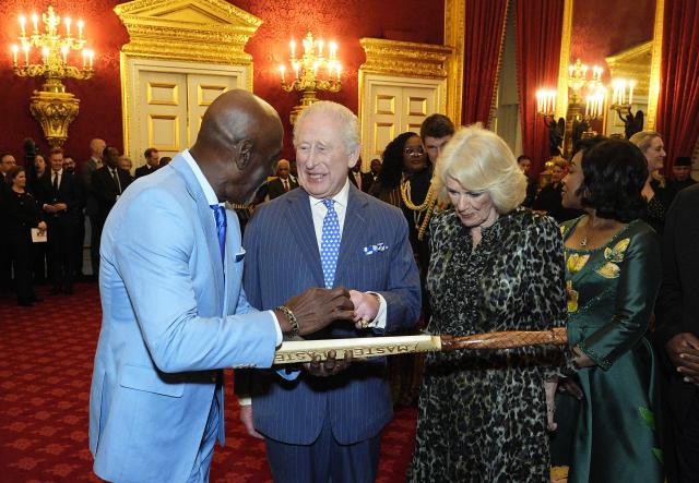 Retired Antiguan cricketer Viv Richards (L) gifts a cricket bat to Britain's King Charles III and Britain's Queen Camilla during the annual Commonwealth Day Reception at St James's Palace in London on March 9, 2026. (Photo by Aaron Chown / POOL / AFP)
