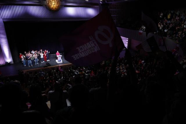 LFI supporters wave flags while LFI's MP and head candidate in the Paris municipal elections Sophia Chikirou delivers a speech during a campaign rally of the left-wing lists candidates ahead of France's upcoming municipal elections at the Mutualite venue in Paris on March 9, 2026.  (Photo by Kenzo TRIBOUILLARD / AFP)