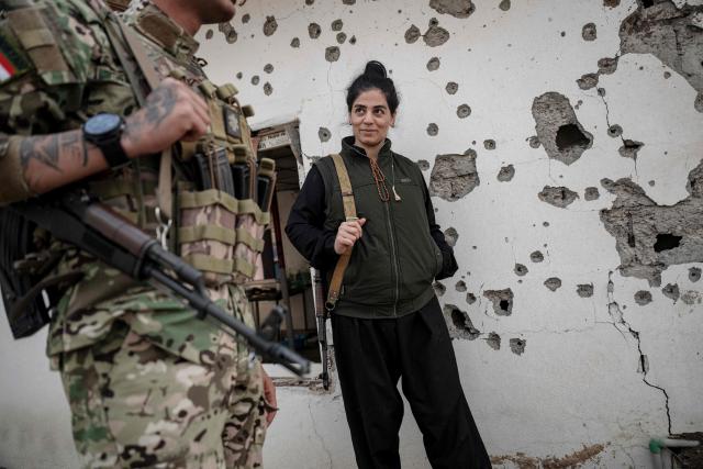 TOPSHOT - Kurdish fighters, a member of The Organization of Iranian Kurdistan Struggle (Sazmani Khabat),  stands in front of a shrapnel scarred wall of a damaged building, following an Iranian drone attack to their base near Erbil,  in Iraq's northern autonomous Kurdish region on March 9, 2026. Iran has designated Kurdish rebels groups as terrorist organisations, and many have previously fought its security forces in Kurdish-majority areas along the border. (Photo by Ozan KOSE / AFP)