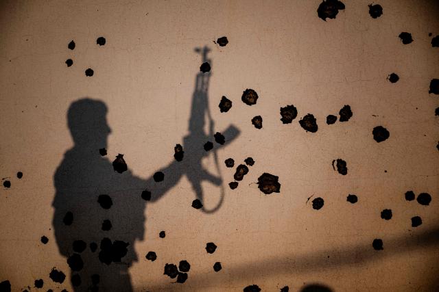 TOPSHOT - The shadow of a Kurdish fighter, a member of The Organization of Iranian Kurdistan Struggle (Sazmani Khabat), falls on the shrapnel scarred wall of a damaged building, following an Iranian drone attack to their base near Erbil,  in Iraq's northern autonomous Kurdish region on March 9, 2026. Iran has designated Kurdish rebels groups as terrorist organisations, and many have previously fought its security forces in Kurdish-majority areas along the border. (Photo by Ozan KOSE / AFP)