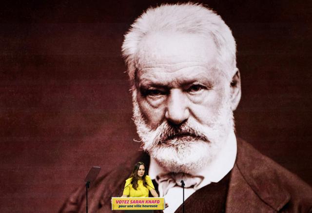French far-right party Reconquete! MEP and candidate for mayor of Paris Sarah Knafo speaks in front of a giant screen displaying a portrait of French writer and politician Victor Hugo during a campaign meeting at the Dome de Paris venue in Paris on March 9, 2026. (Photo by Dimitar DILKOFF / AFP)