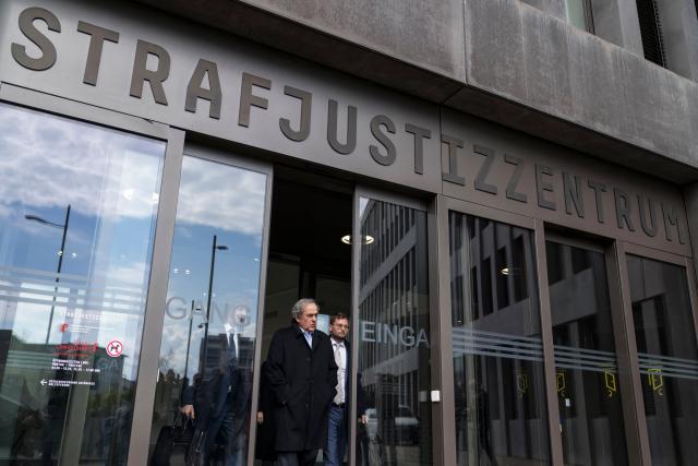 (FILES) Former UEFA president Michel Platini (C) exits the courthouse after the verdict of an appeal by Swiss Attorney General's office against former UEFA and FIFA presidents over a suspected fraudulent payment, in Muttenz near Basel, on March 25, 2025. Former UEFA president Michel Platini, who has filed a defamation suit against three former FIFA officials, said on March 9, 2026 that he was determined ‘not to let go of the people who have hurt [him]’. (Photo by Fabrice COFFRINI / AFP)