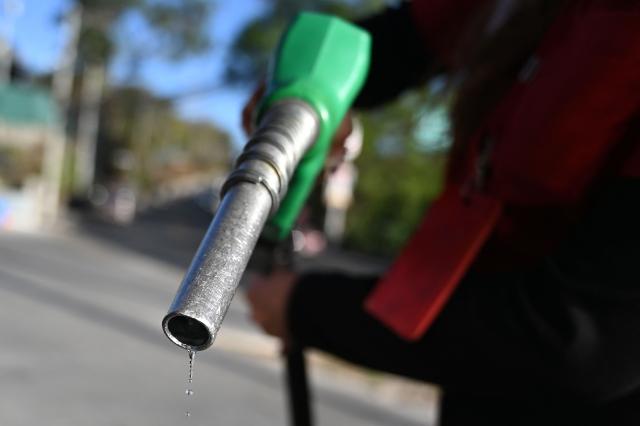 An attendant holds a fuel pump at a gas station in Tegucigalpa on March 9, 2026. The prices of petroleum derivatives soared on March 9 in Honduras due to the war in the Middle East. (Photo by Orlando SIERRA / AFP)