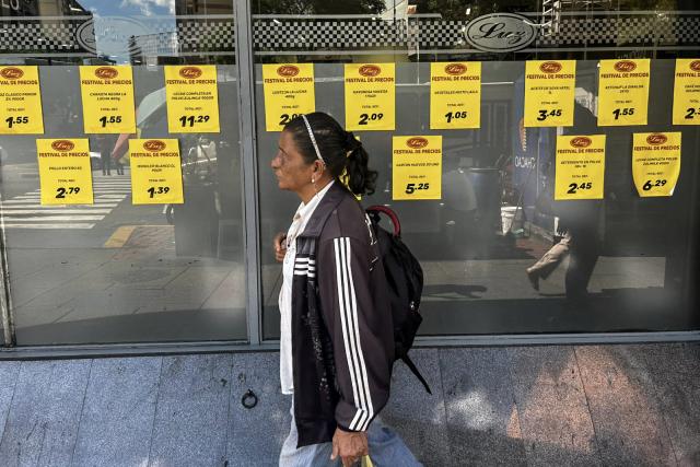 A woman walks in front of price signs on a supermarket window in Caracas on March 9, 2026. Venezuela closed 2025 with the highest inflation in the world: 475%, a brutal acceleration tied to the currency chaos triggered by the tightening of US sanctions against the ousted President Nicolas Maduro. (Photo by Juan BARRETO / AFP)