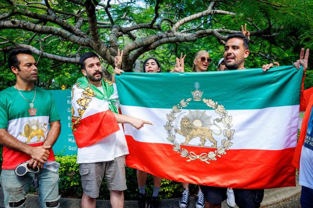 Members of the Iranian community in Australia stand with a pre-revolution Iranian flag with lion and sun emblem in a show of support outside the Royal Pines Resort, where members of the Iranian women’s football team are staying, on the Gold Coast on March 10, 2026. Five players in Iran's visiting women's football team have taken asylum in Australia over fears of persecution at home for not singing the national anthem before a match, the government said on March 10. (Photo by Patrick HAMILTON / AFP)