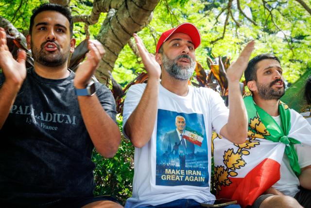 Members of the Iranian community in Australia, including a man wearing a T-shirt depicting Reza Pahlavi, the son of Iran's late shah, gesture in a show of support outside the Royal Pines Resort, where members of the Iranian women’s football team are staying, on the Gold Coast on March 10, 2026. Five players in Iran's visiting women's football team have taken asylum in Australia over fears of persecution at home for not singing the national anthem before a match, the government said on March 10. (Photo by Patrick HAMILTON / AFP)