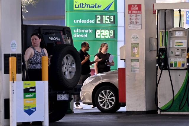 People fill their cars as a sign outside a fuel station in Melbourne on March 10, 2026 shows the soaring price of petrol and diesel prices due to the Middle East conflict. Global oil prices have climbed dramatically since the war, prompting warnings that high fuel prices could drive inflation above 5 per cent in Australia. (Photo by William WEST / AFP)