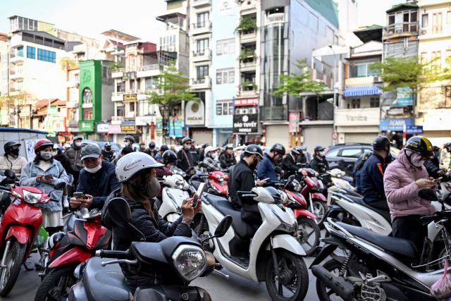 Motorists queue to pump gasoline into their vehicle at a gas station in Hanoi on March 10, 2026. Vietnam announced on March 9 it was scrapping tariffs on fuel imports, as the US-Israeli war with Iran disrupts oil supplies and pushes prices to their highest level since 2022. (Photo by Nhac NGUYEN / AFP)