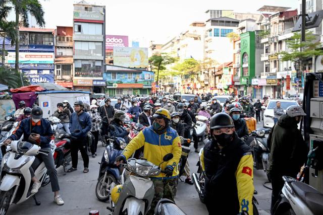 Motorists queue to pump gasoline into their vehicle at a gas station in Hanoi on March 10, 2026. Vietnam announced on March 9 it was scrapping tariffs on fuel imports, as the US-Israeli war with Iran disrupts oil supplies and pushes prices to their highest level since 2022. (Photo by Nhac NGUYEN / AFP)