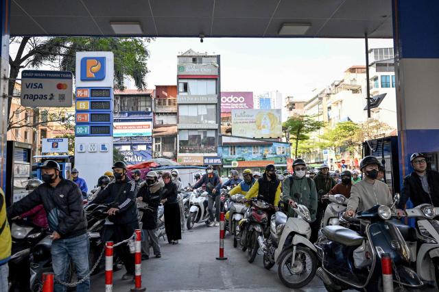 Motorists queue to pump gasoline into their vehicle at a gas station in Hanoi on March 10, 2026. Vietnam announced on March 9 it was scrapping tariffs on fuel imports, as the US-Israeli war with Iran disrupts oil supplies and pushes prices to their highest level since 2022. (Photo by Nhac NGUYEN / AFP)