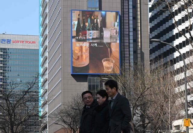 Pedestrians walk past a billboard showing a promotional video for tourism in Japan's Fukushima region, in downtown Seoul on March 10, 2026. A tourism promotion video for Japan's tsunami-hit Fukushima region is being shown on billboards across the South Korean capital Seoul for the first time since the 2011 nuclear accident, a Japanese official said on March 10. (Photo by Jung Yeon-je / AFP)