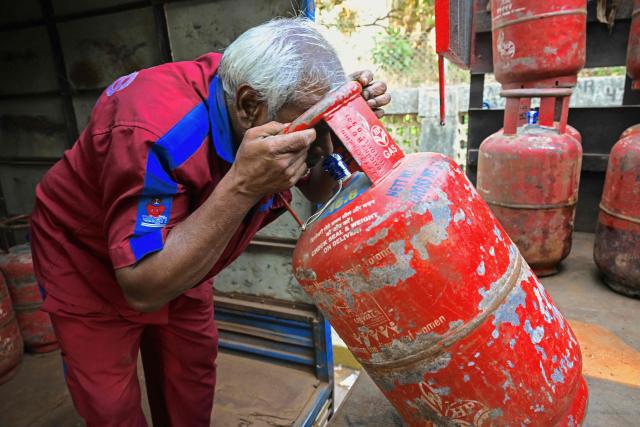 A delivery staff inspects liquefied petroleum gas (LPG) cylinders for leakage while unloading them from a truck at a distribution point in Mumbai on March 10, 2026. Oil prices tanked and equities rallied on March 10, following a wild day of swings that came after Donald Trump said the US-Israel war on Iran would be ending earlier than thought. Trump also said he would waive some Ukraine war-linked sanctions on Russian oil sales to India, with White House officials reassuring G7 partners that the move would only be temporary. (Photo by Indranil MUKHERJEE / AFP)