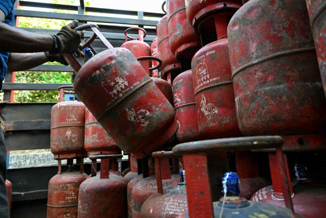 A delivery staff unloads liquefied petroleum gas (LPG) cylinders from a truck at a distribution point in Mumbai on March 10, 2026. Oil prices tanked and equities rallied on March 10, following a wild day of swings that came after Donald Trump said the US-Israel war on Iran would be ending earlier than thought. Trump also said he would waive some Ukraine war-linked sanctions on Russian oil sales to India, with White House officials reassuring G7 partners that the move would only be temporary. (Photo by Indranil MUKHERJEE / AFP)