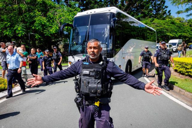 TOPSHOT - Police officers clear the road for a departing bus transporting members of the Iranian Women’s Asia Cup football team to the airport, after members of the Iranian community in Australia attempted to block its path, outside the Royal Pines Resort on the Gold Coast on March 10, 2026. Five players from Iran's visting women's football team claimed asylum in Australia on March 10, seeking protection after they were branded "traitors" at home for refusing to sing the national anthem. (Photo by Patrick HAMILTON / AFP)