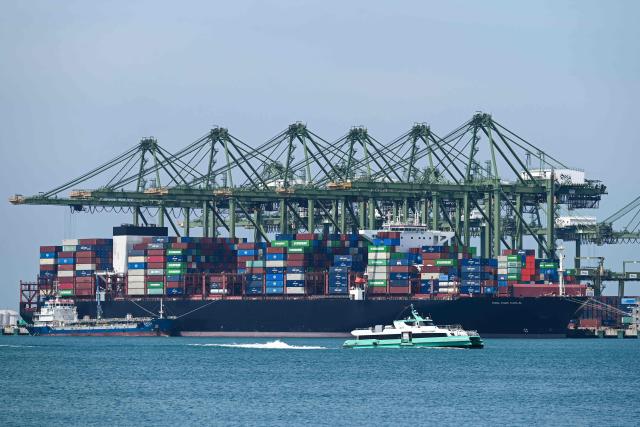 An oil tanker (L) refuels a container vessel docked at Pasir Panjang port terminal in Singapore on March 10, 2026. (Photo by Roslan RAHMAN / AFP)
