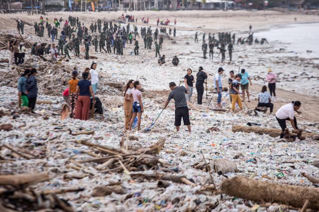 Workers and residents clear marine debris and plastic waste washed ashore during the monsoon season from Jimbaran Beach on Indonesia's resort island of Bali on March 10, 2026. (Photo by Lana Priatna / AFP)