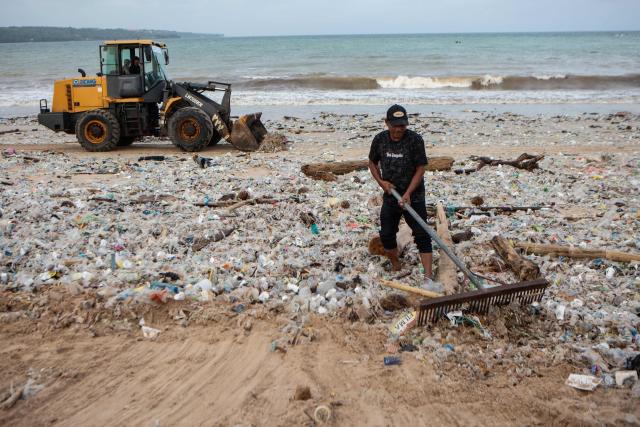 Workers and residents clear marine debris and plastic waste washed ashore during the monsoon season from Jimbaran Beach on Indonesia's resort island of Bali on March 10, 2026. (Photo by Lana Priatna / AFP)