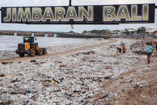 Workers and residents clear marine debris and plastic waste washed ashore during the monsoon season from Jimbaran Beach on Indonesia's resort island of Bali on March 10, 2026. (Photo by Lana Priatna / AFP)