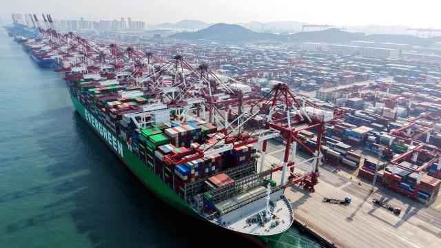 A cargo ship and containers are seen at a port in Qingdao, eastern China's Shandong province on March 10, 2026. (Photo by CN-STR / AFP) / China OUT