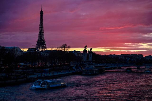 River boats sail up the Seine river as the Eiffel Tower is silhouetted at sunset, on March 9, 2026. (Photo by Christophe DELATTRE / AFP)