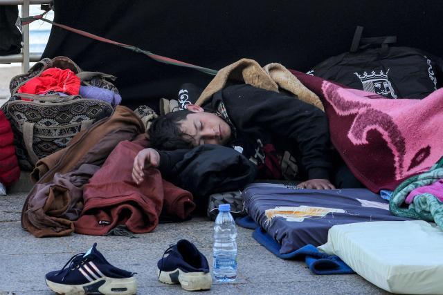 TOPSHOT - A child sleeps alongside family belongings in a makeshift encampment along the waterfront in Beirut on March 10, 2026, as civilians who fled the city's southern suburbs due to Israeli bombardment remain displaced. Lebanese authorities said on March 9 that Israel's attacks since March 2 have killed at least 486 people and wounded at least 1,313, with more than 660,000 registered as displaced and 120,000 sleeping at official shelters. Lebanon was drawn into the Middle East war when Iran-backed Hezbollah attacked Israel, in response to the killing of the Iranian supreme leader in US-Israeli strikes on February 28. (Photo by Anwar AMRO / AFP) / Attention editors: AFP covers the war in the Middle East through its extensive regional network, including bureaus in Tehran, Jerusalem and several neighboring countries.Since the start of the conflict, journalists have been working under increasingly restrictive conditions. Authorities in several countries have limited reporters movements, photo and live video coverage from sensitive locations. Some governments and armed groups have banned images of missile or drone strikes and other security-related sites. / 