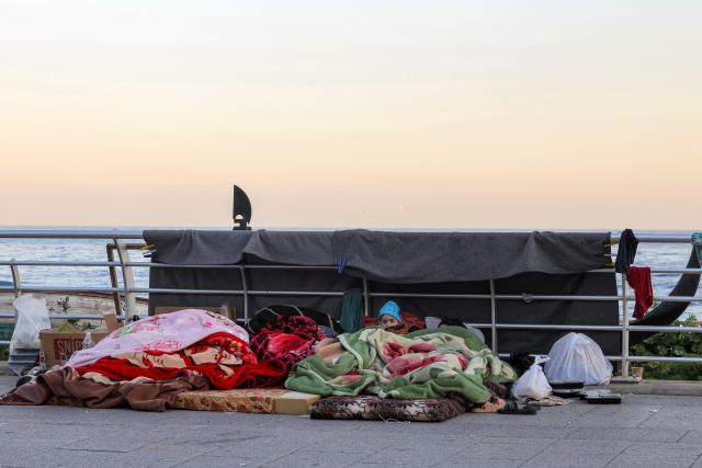 A boy looks on while lying under a blanket alongside family belongings in a makeshift encampment along the waterfront in Beirut on March 10, 2026, as civilians who fled the city's southern suburbs due to Israeli bombardment remain displaced. Lebanese authorities said on March 9 that Israel's attacks since March 2 have killed at least 486 people and wounded at least 1,313, with more than 660,000 registered as displaced and 120,000 sleeping at official shelters. Lebanon was drawn into the Middle East war when Iran-backed Hezbollah attacked Israel, in response to the killing of the Iranian supreme leader in US-Israeli strikes on February 28. (Photo by Anwar AMRO / AFP) / Attention editors: AFP covers the war in the Middle East through its extensive regional network, including bureaus in Tehran, Jerusalem and several neighboring countries.Since the start of the conflict, journalists have been working under increasingly restrictive conditions. Authorities in several countries have limited reporters movements, photo and live video coverage from sensitive locations. Some governments and armed groups have banned images of missile or drone strikes and other security-related sites. / 