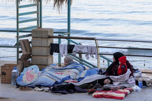 A woman sits with children wrapped in blankets in a makeshift encampment along the waterfront in Beirut on March 10, 2026, as civilians who fled the city's southern suburbs due to Israeli bombardment remain displaced. Lebanese authorities said on March 9 that Israel's attacks since March 2 have killed at least 486 people and wounded at least 1,313, with more than 660,000 registered as displaced and 120,000 sleeping at official shelters. Lebanon was drawn into the Middle East war when Iran-backed Hezbollah attacked Israel, in response to the killing of the Iranian supreme leader in US-Israeli strikes on February 28. (Photo by Anwar AMRO / AFP) / Attention editors: AFP covers the war in the Middle East through its extensive regional network, including bureaus in Tehran, Jerusalem and several neighboring countries.Since the start of the conflict, journalists have been working under increasingly restrictive conditions. Authorities in several countries have limited reporters movements, photo and live video coverage from sensitive locations. Some governments and armed groups have banned images of missile or drone strikes and other security-related sites. / 