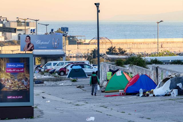 A man walks past tents at a makeshift encampment along the waterfront in Beirut on March 10, 2026, as civilians who fled the city's southern suburbs due to Israeli bombardment remain displaced. Lebanese authorities said on March 9 that Israel's attacks since March 2 have killed at least 486 people and wounded at least 1,313, with more than 660,000 registered as displaced and 120,000 sleeping at official shelters. Lebanon was drawn into the Middle East war when Iran-backed Hezbollah attacked Israel, in response to the killing of the Iranian supreme leader in US-Israeli strikes on February 28. (Photo by Anwar AMRO / AFP) / Attention editors: AFP covers the war in the Middle East through its extensive regional network, including bureaus in Tehran, Jerusalem and several neighboring countries.Since the start of the conflict, journalists have been working under increasingly restrictive conditions. Authorities in several countries have limited reporters movements, photo and live video coverage from sensitive locations. Some governments and armed groups have banned images of missile or drone strikes and other security-related sites. / 