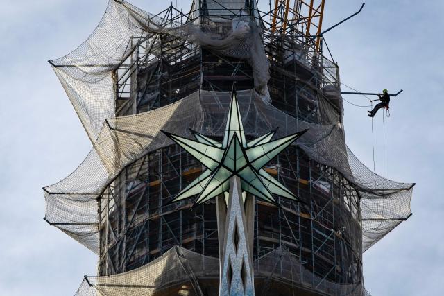 A worker hangs from scaffolding near the star of the tower of the Virgin Mary as works continue on Spanish architect Antoni Gaudi's Sagrada Familia Basilica in Barcelona on March 10, 2026. Iconic monument designed more than 140 years ago, Barcelona's eternally unfinished Sagrada Familia has grown to become the world's tallest church. (Photo by Josep LAGO / AFP)