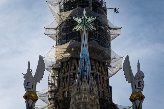 A worker hangs from scaffolding near the star of the tower of the Virgin Mary as works continue on Spanish architect Antoni Gaudi's Sagrada Familia Basilica in Barcelona on March 10, 2026. Iconic monument designed more than 140 years ago, Barcelona's eternally unfinished Sagrada Familia has grown to become the world's tallest church. (Photo by Josep LAGO / AFP)