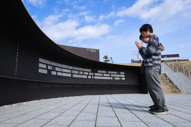 People pray at the Kamaishi Prayer Park, a memorial facility for the victims of the 2011 earthquake and tsunami disaster in Kamaishi City, Iwate Prefecture on March 10, 2026, the day before the 15th anniversary. (Photo by JIJI PRESS / AFP) / Japan OUT