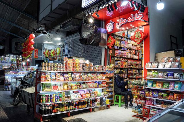A vendor browses a phone as he waits by his shop at a bazaar in Tehran on March 10, 2026. Iran marked the appointment of Ayatollah Mojtaba Khamenei to replace his father as its supreme leader with a new barrage of missiles against Israel and the Gulf states on March 9, as the Middle East war sent oil prices soaring. (Photo by AFP) / Attention editors: AFP covers the war in the Middle East through its extensive regional network, including bureaus in Tehran, Jerusalem, and several neighboring countries. Since the start of the conflict, journalists have been working under increasingly restrictive conditions. Authorities in several countries have limited reporters' movements, photo and live video coverage from sensitive locations. Some governments and armed groups have banned images of missile or drone strikes and other security-related sites. / 