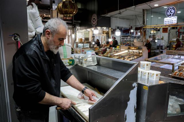 A vendor cuts fish at his stall in a bazaar in Tehran on March 10, 2026. Iran marked the appointment of Ayatollah Mojtaba Khamenei to replace his father as its supreme leader with a new barrage of missiles against Israel and the Gulf states on March 9, as the Middle East war sent oil prices soaring. (Photo by AFP) / Attention editors: AFP covers the war in the Middle East through its extensive regional network, including bureaus in Tehran, Jerusalem, and several neighboring countries. Since the start of the conflict, journalists have been working under increasingly restrictive conditions. Authorities in several countries have limited reporters' movements, photo and live video coverage from sensitive locations. Some governments and armed groups have banned images of missile or drone strikes and other security-related sites. / 
